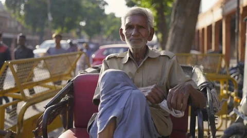 An old man sitting next to a busy road on the cycle rickshaw Stock Footage 147010684