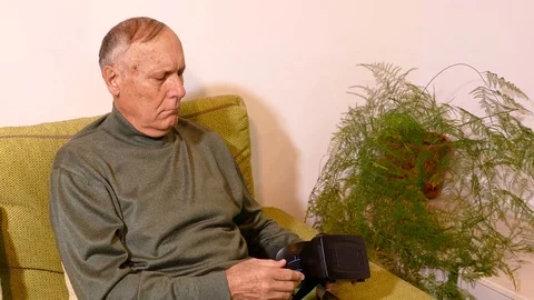 Old man sitting on the sofa in the living room and using tablet Stock Footage 71896029