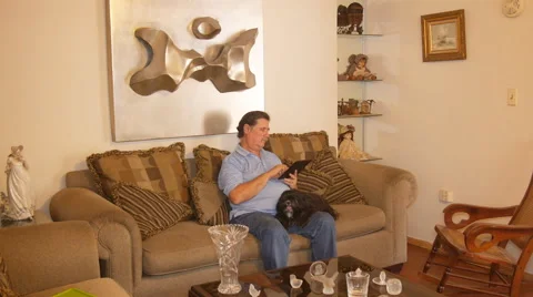 Old man in sofa with Ipad-tablet and pet dog Stock Footage 50885741