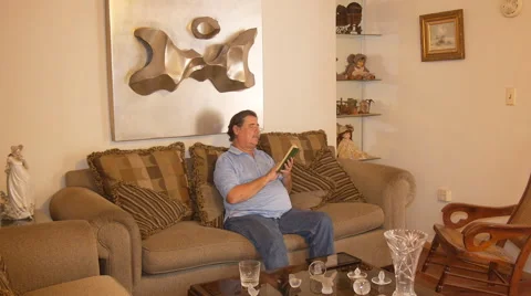 Old man in sofa reading the Bible out loud Stock Footage 50876064