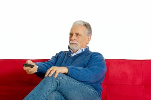 Old man on the sofa with television remote control Stock Photos
