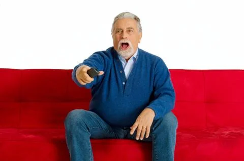 Old man on the sofa with television remote control Stock Photos