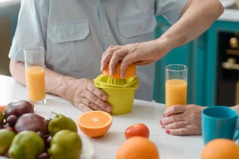 Old man squeezing an orange using a plain juicer Stock-Fotos