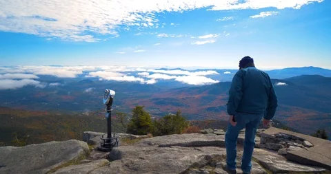 Old Man Stands on Edge of Mountain Cliff, Overlooking Lake &amp; Forest Stock Footage 102401518