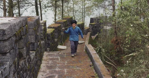 A old man, stone building worker walking on the southern great wall of china in Vídeos de archivo 201093875