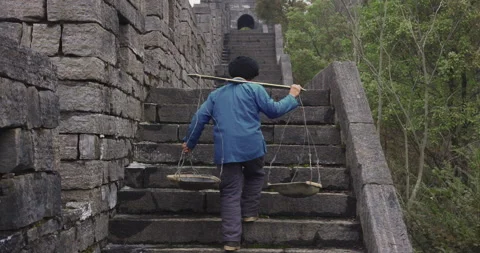 A old man, stone building worker walking on the southern great wall of china in Vidéo 201095941