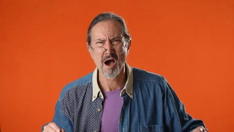 Old man struggles to hear, having difficulty hearing, isolated on solid orange Stock Footage 207778505
