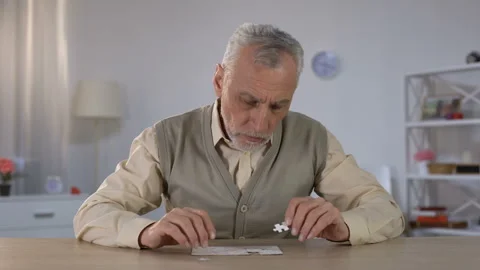 Old man successfully combining puzzle, exercise to improve cognitive function Stock Footage 108157297