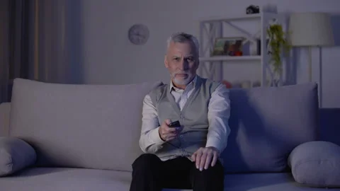 Old man switching channels with remote control, bored and annoyed with ads Stock Footage 108136687