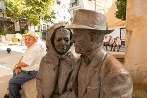 An old man taking a break next to a statue in Lanjarón, Spain Stock Photos