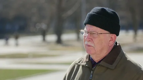 Old man taking off his glasses and admiring the view outdoors in sunny winter Видео 104256185