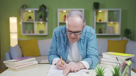 Old man taking notes about the book he's reading. Stock Footage 237795218