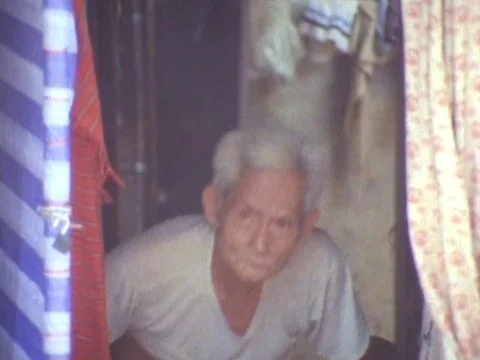 Old man taking a seat under a shed peeping outside Stock Footage 79880562