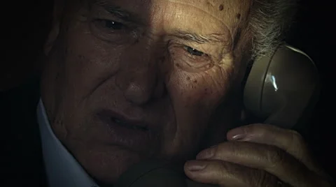 Old man talking using a landline phone in the gloom Stock Footage 68760362