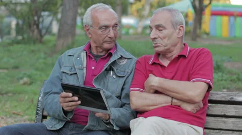 Old man teaching his elderly friend to use a new tablet PC Stock Footage 32357123