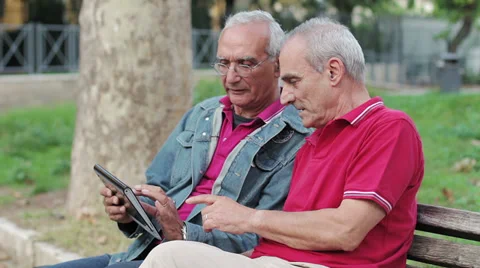 Old man teaching his elderly friends to use a new tablet PC Stockbeeldmateriaal 32357217