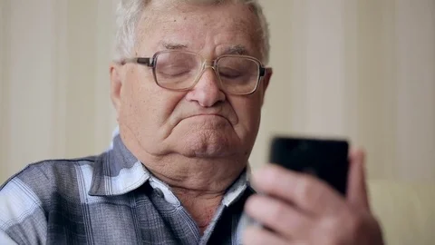Old man text messaging through mobile phone on sofa Stock Footage 74360335