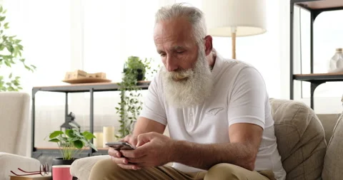 Old man text messaging using mobile phone at home Stock-Footage 138317417