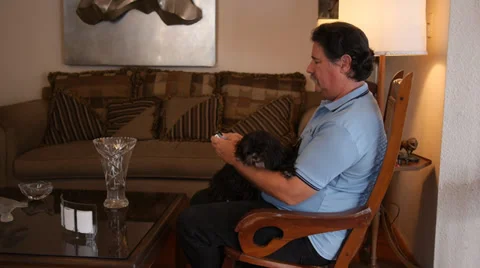 Old man texting with cellular with Shih Tzu black dog in rocking chair Stock Footage 30903799