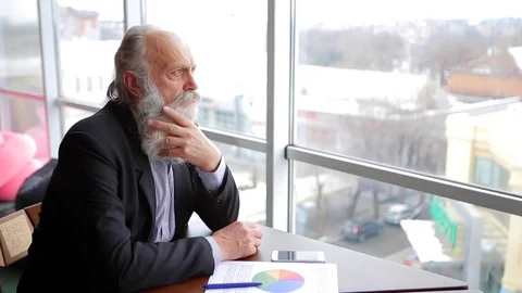 Old Man Thinking Aloud About Country's Economy, Sitting at Table in Company's Stock Footage 73771894