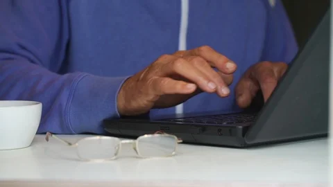 Old man types on laptop by cup and glasses on table closeup Stock Footage 118249790