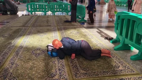 Old man Umrah pilgrim resting on a carpet outside the Prophet's Mosque Vídeo Stock 332963459