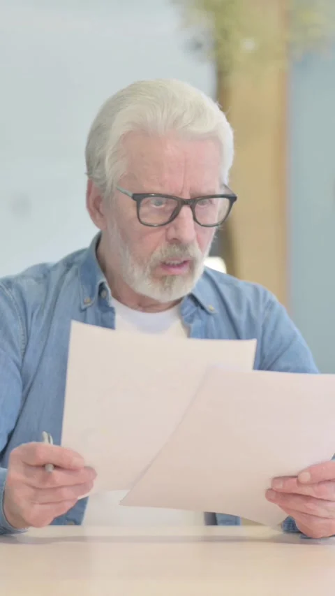 Old Man Upset by Loss Reading Documents, vertical video Stock-Footage 329107048