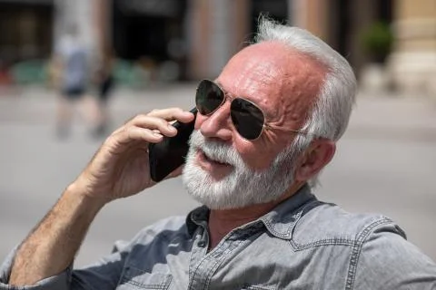 Old man use internet application on smartphone, seating on bench,  stock phot Stock Photos