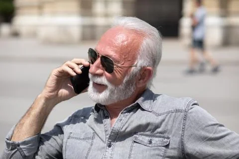 Old man use internet application on smartphone, seating on bench,  stock phot Stock Photos