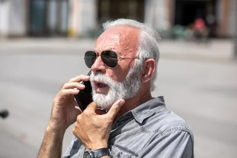 Old man use internet application on smartphone, seating on bench,  stock phot Stock Photos