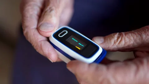 Old man using digital pulse oximeter for controlling oxygen saturation in blood Stock Footage 148499358