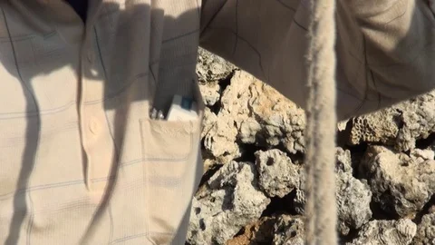 An old man is using a rope to draw water from a well. Closeup. Stock Footage 72470751