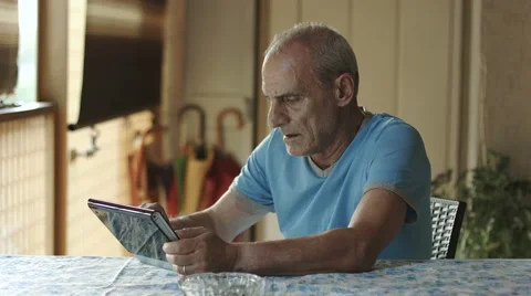 Old man is using tablet computer at home: elderly, technology, internet Stock Footage 41757394