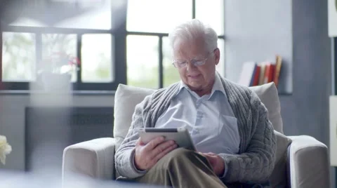 Old man is using tablet computer at home Stock Footage