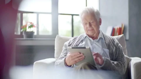 Old man is using tablet computer at home Stock Footage 63325844
