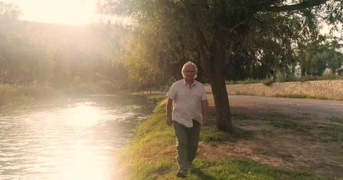 Old man walk by the river at sunset Stock Footage 124381850
