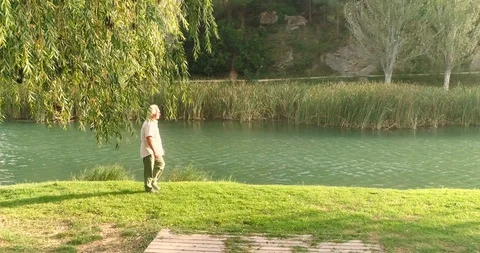 Old man walking along the river at sunset Stock Footage 124381200