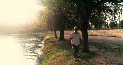 Old man walking along the river bank Stock Footage 124382082