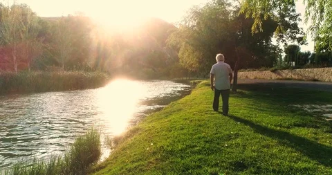 Old man walking along river Stock Footage 124384716