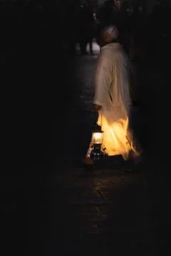 Old man walking with an illuminated lantern during night hours in Marrakesh,  Stock Photos