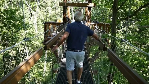 Old man walking Murch Canopy Walk holding on handholds Stock Footage 78248742