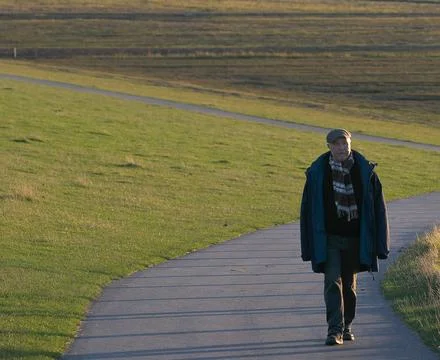Old Man Walking Rural Path Uphill Alone And Looking Concerned In Sunset Stock Photos