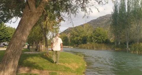 Old man walking through the field by the river Stock Footage 124381505