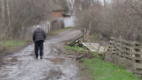 An old man walks down a dirt road among the ruins. Ukraine war. Chernihiv. Stock Footage 254208140