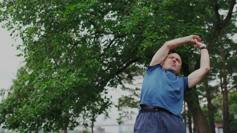 Old Man warm up his Back and Muscles Outdoor. Recreation or Physical Relaxing Stock Footage 148465936
