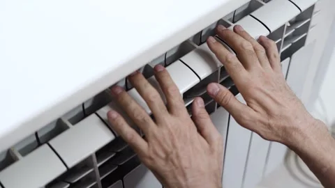 Old man warming hands on radiator grill Stock Footage 297704383