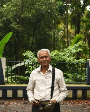 An old man, wearing spectacles and shirt, standing alone in garden Stock-Fotos