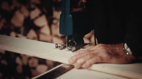 Old man working with a jigsaw cutting a piece of wood in a straight line Stock Footage 139755423
