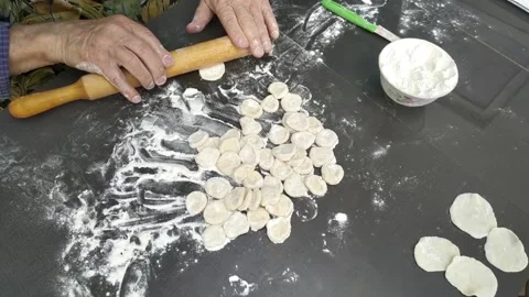 The old man's hands roll out small circles of dough. Stock Footage 137132642