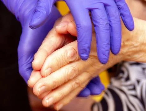 Old man's hands support hands in medical gloves Stock Photos